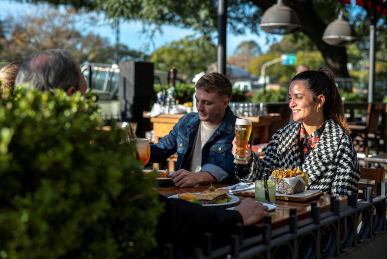 Grupo de amigos disfrutando cerveza y picada en una mesa al aire libre durante el happy hour en Pizza Cero en Buenos Aires