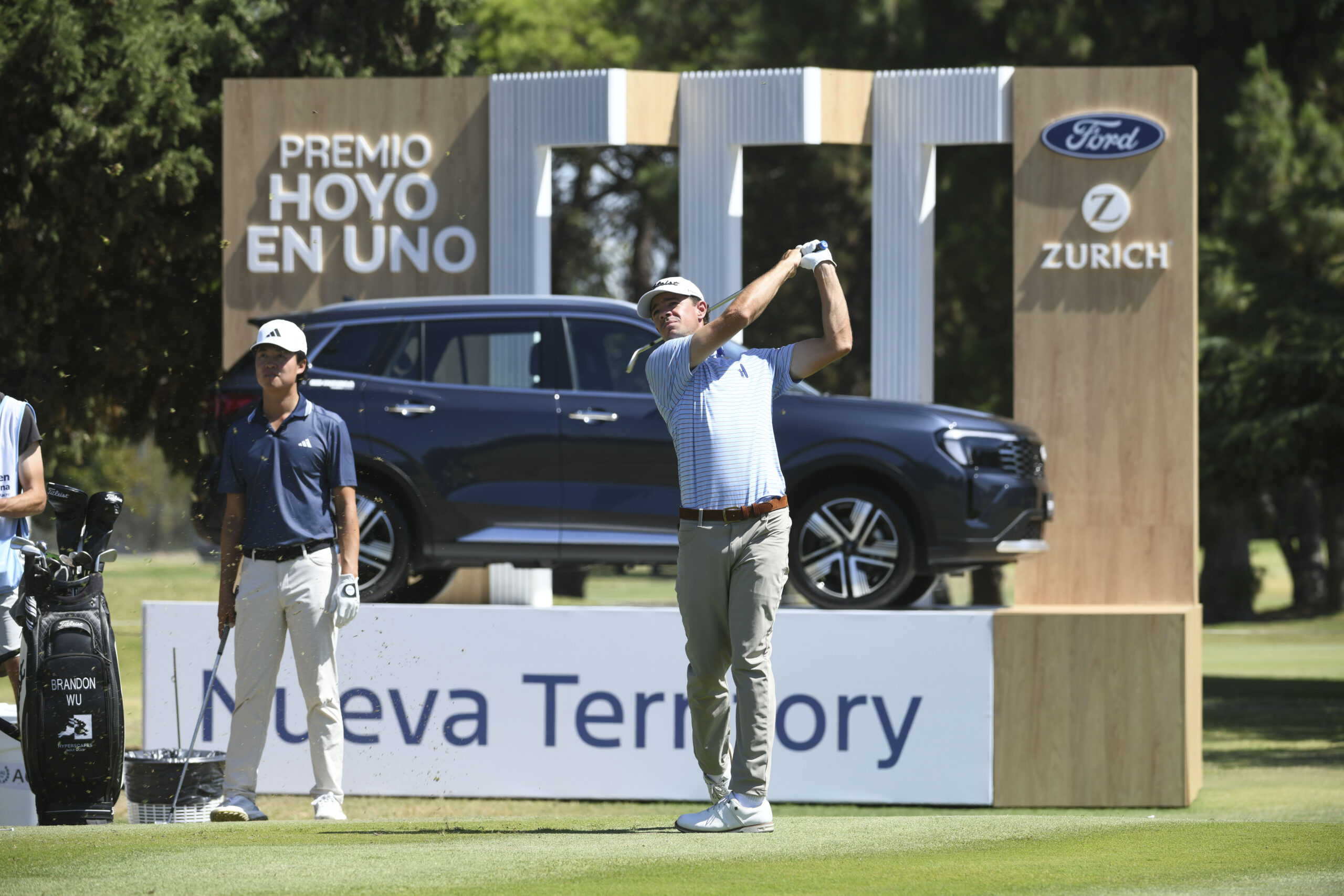 Golfista ejecutando un golpe en el Abierto de la República con un vehículo Ford exhibido en el campo de golf durante el torneo