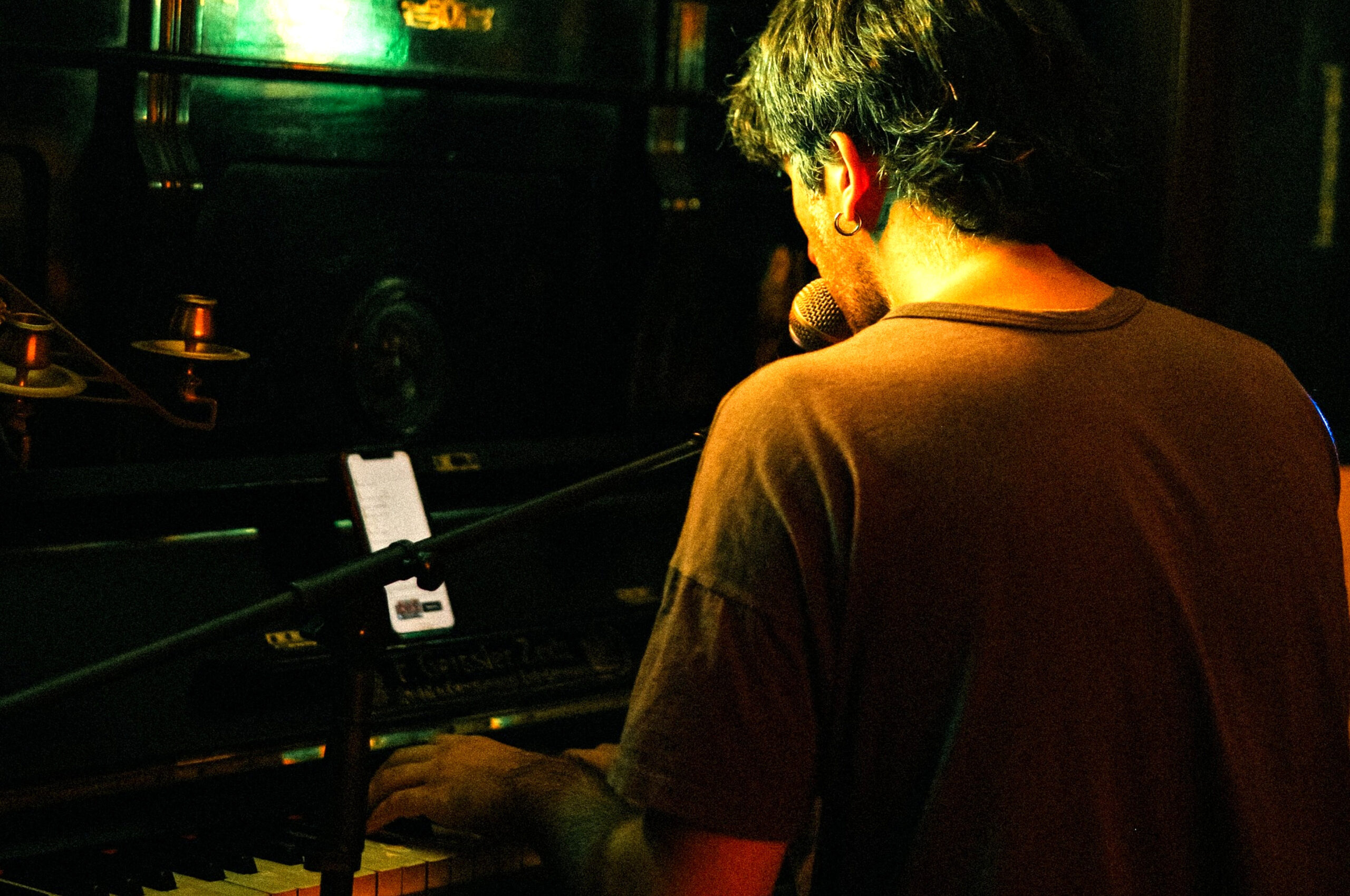 Músico tocando el piano y cantando en vivo durante una noche de Piano Bar con rock nacional y micrófono abierto en el bar Puchero de Villa Luro