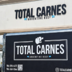 Camión de Total Carnes frente a su local en Estados Unidos con branding de carne argentina y fachada del establecimiento