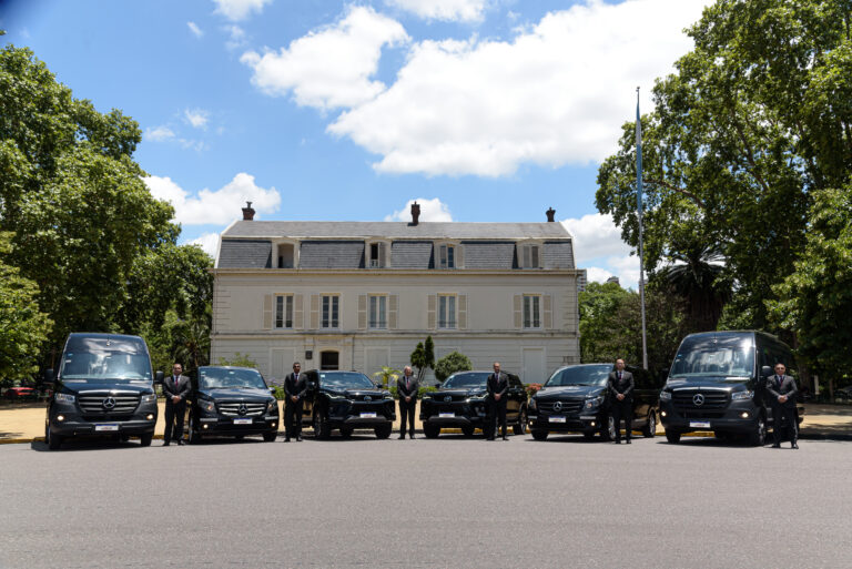 Flota de vehículos ejecutivos con choferes uniformados frente a un edificio institucional en el marco de servicios de logística para eventos