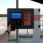 Usuario paga un peaje con celular mediante sistema contactless frente a una terminal electrónica en autopista