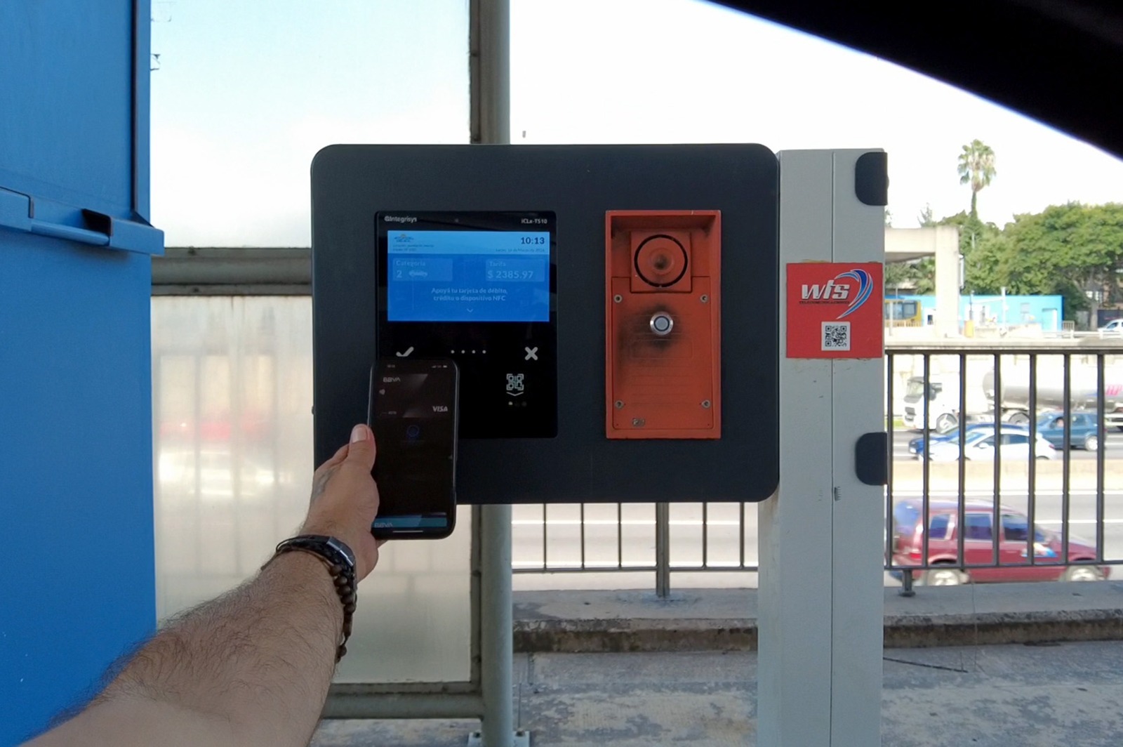 Usuario paga un peaje con celular mediante sistema contactless frente a una terminal electrónica en autopista
