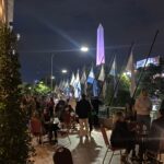 Personas degustando vino en una terraza nocturna con vista al Obelisco en un evento gastronómico en Buenos Aires