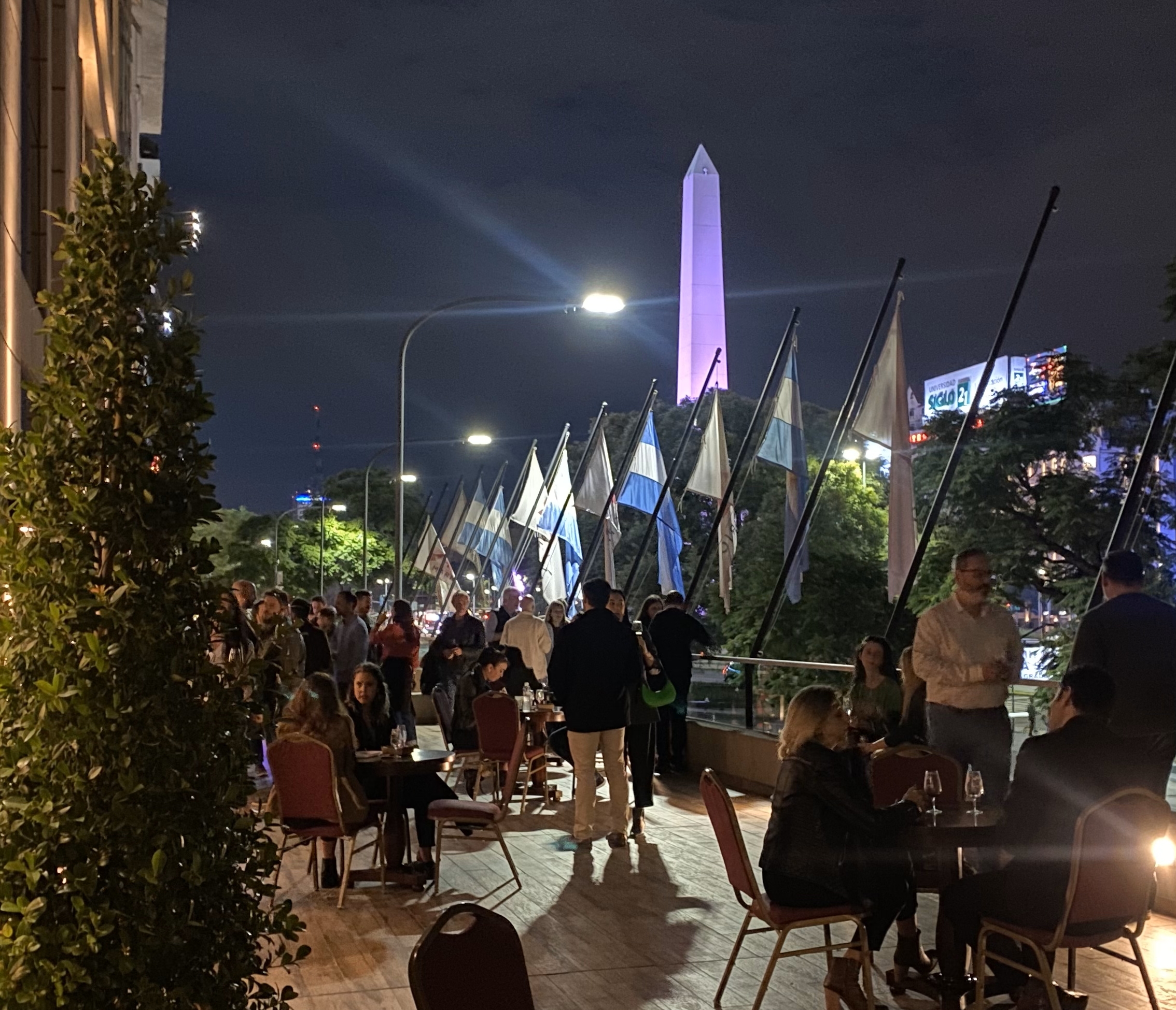 Personas degustando vino en una terraza nocturna con vista al Obelisco en un evento gastronómico en Buenos Aires