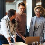 Equipo de trabajo diverso colaborando en una oficina moderna con laptops y ambiente laboral positivo en Argentina