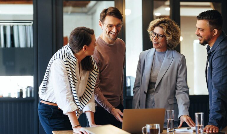 Equipo de trabajo diverso colaborando en una oficina moderna con laptops y ambiente laboral positivo en Argentina