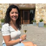 Florencia Cortés frente a Bodega Cruzat sosteniendo una copa de espumante en un entorno vitivinícola en Mendoza