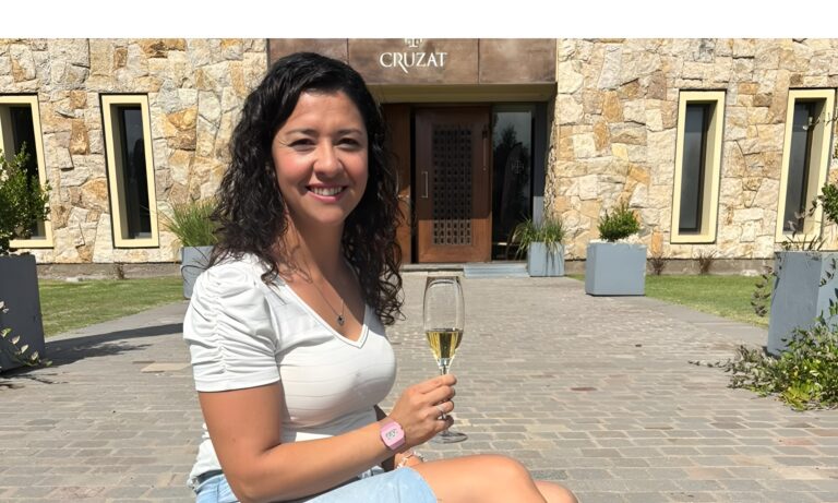 Florencia Cortés frente a Bodega Cruzat sosteniendo una copa de espumante en un entorno vitivinícola en Mendoza
