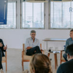Panel de emprendedores tecnológicos en una charla sobre innovación y futuro digital frente a una audiencia en un espacio corporativo moderno