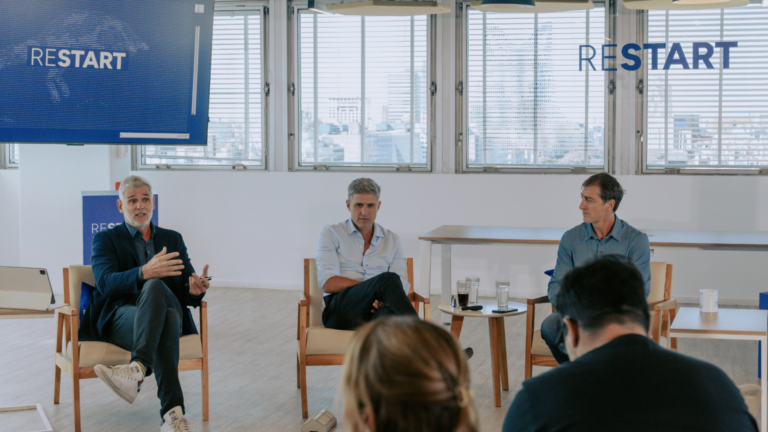 Panel de emprendedores tecnológicos en una charla sobre innovación y futuro digital frente a una audiencia en un espacio corporativo moderno