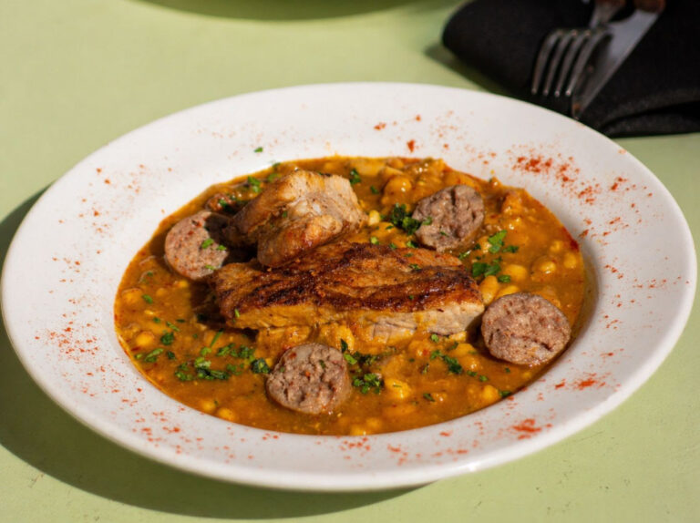 Plato de locro patrio con chorizo, panceta y maíz servido en Casa Zarautz durante la propuesta especial de 25 de Mayo en Palermo