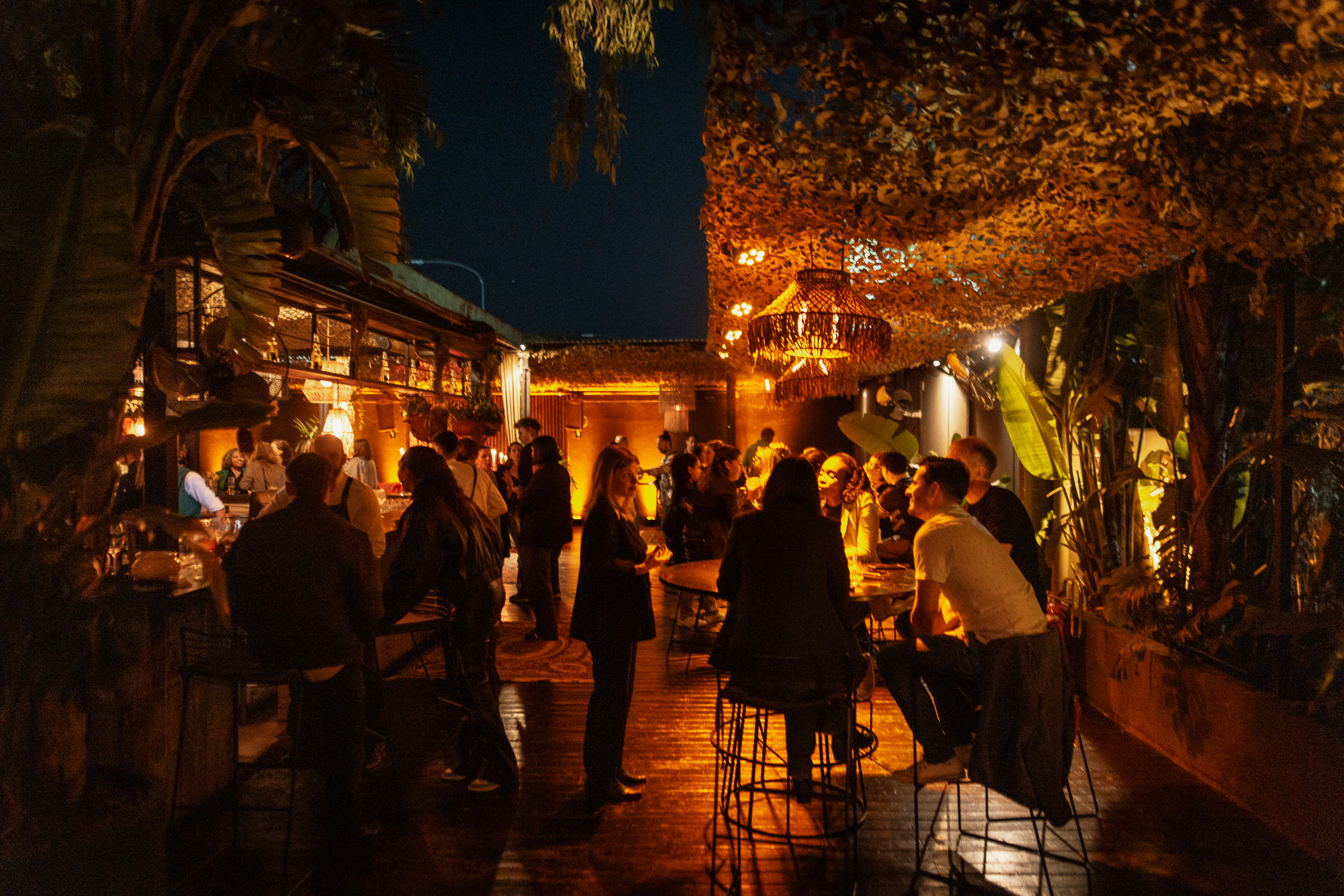 Personas disfrutando una cena en el espacio exterior de Enero Restaurant con ambientación cálida y vista nocturna junto al río