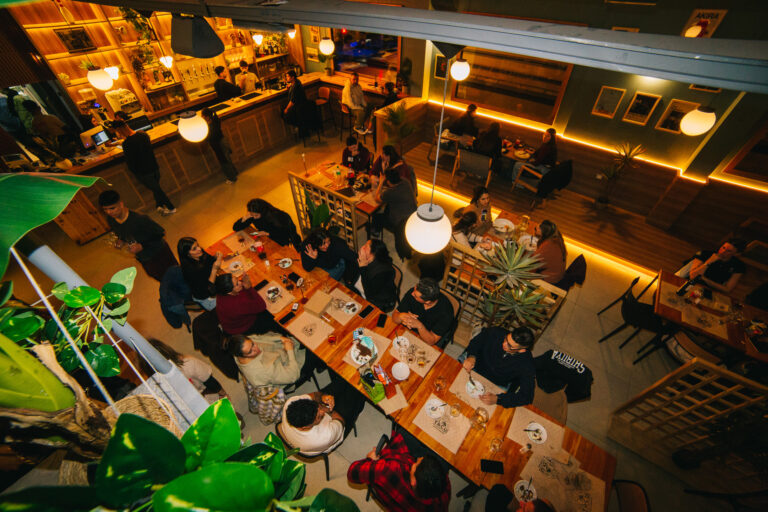 Vista aérea del interior de TACU Resto & Bowling con personas cenando y compartiendo en un espacio gastronómico moderno en zona norte