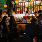 Interior de Punto Mona con barra de coctelería, música y público disfrutando de una noche gastronómica y social en Chacarita