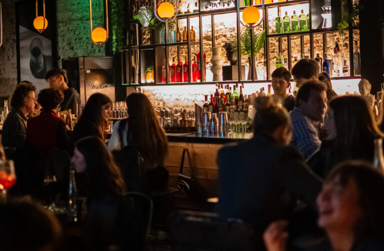 Interior de Punto Mona con barra de coctelería, música y público disfrutando de una noche gastronómica y social en Chacarita