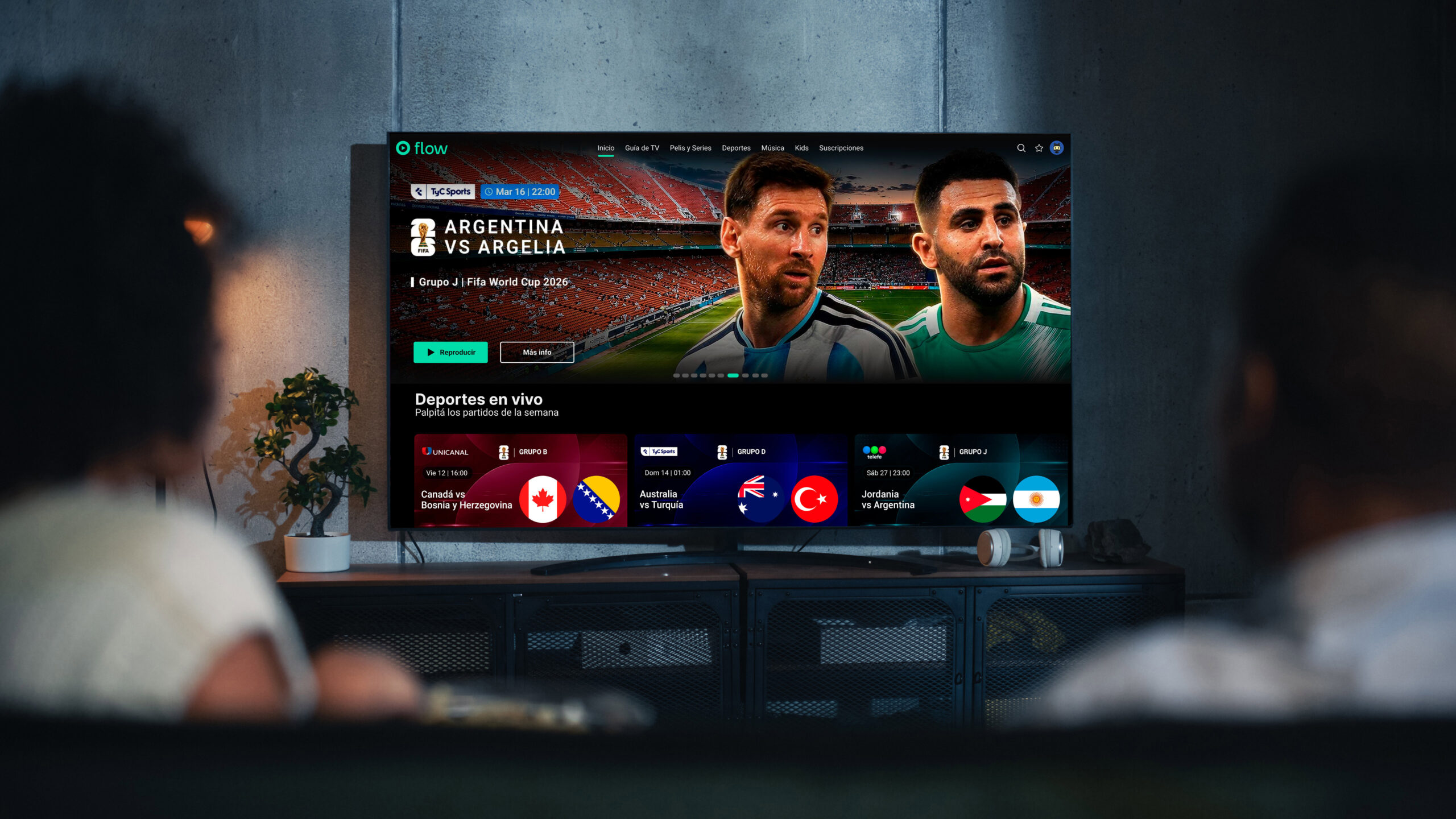 Pantalla de Flow en una Smart TV con contenidos deportivos personalizados mientras dos personas observan la plataforma desde el living de su hogar