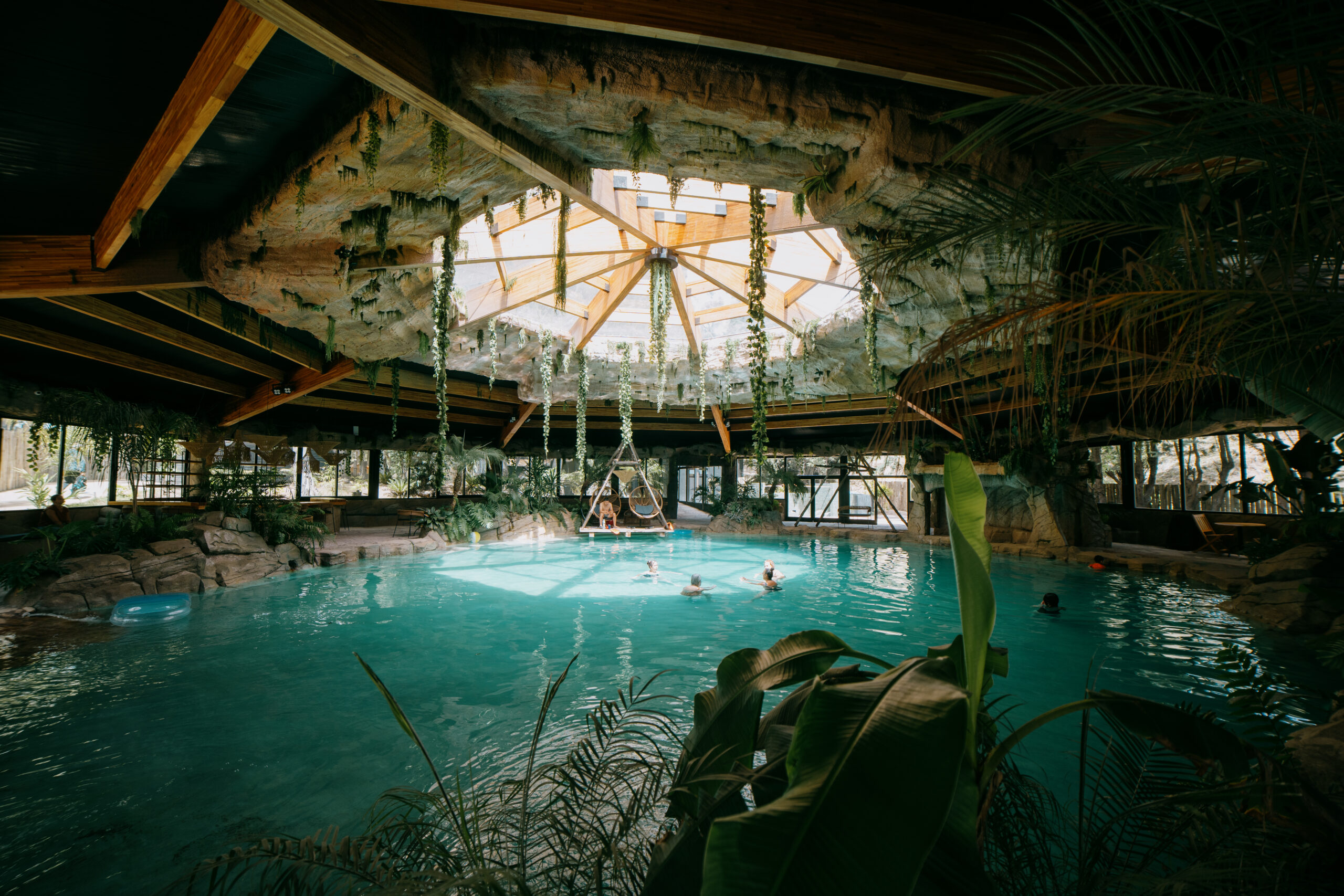 Vista interior de un xenote cubierto con aguas turquesas, vegetación colgante y luz natural, uno de los atractivos turísticos de un destino de la Costa Atlántica