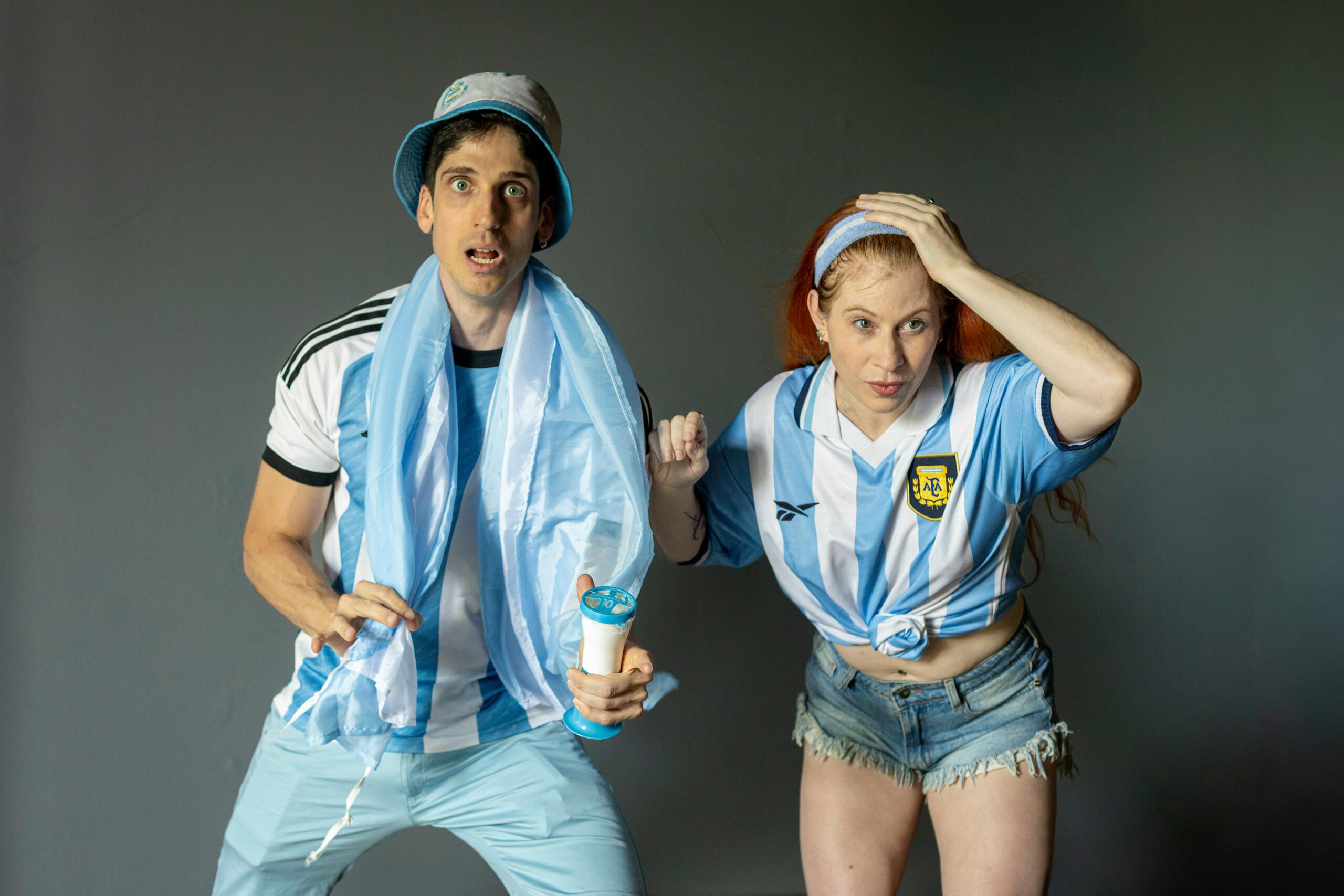 Dos hinchas argentinos observan un partido de fútbol con atención y expectativa, representando los valores de compromiso, trabajo en equipo, confianza y liderazgo que inspiran tanto a la Scaloneta como al ámbito empresarial