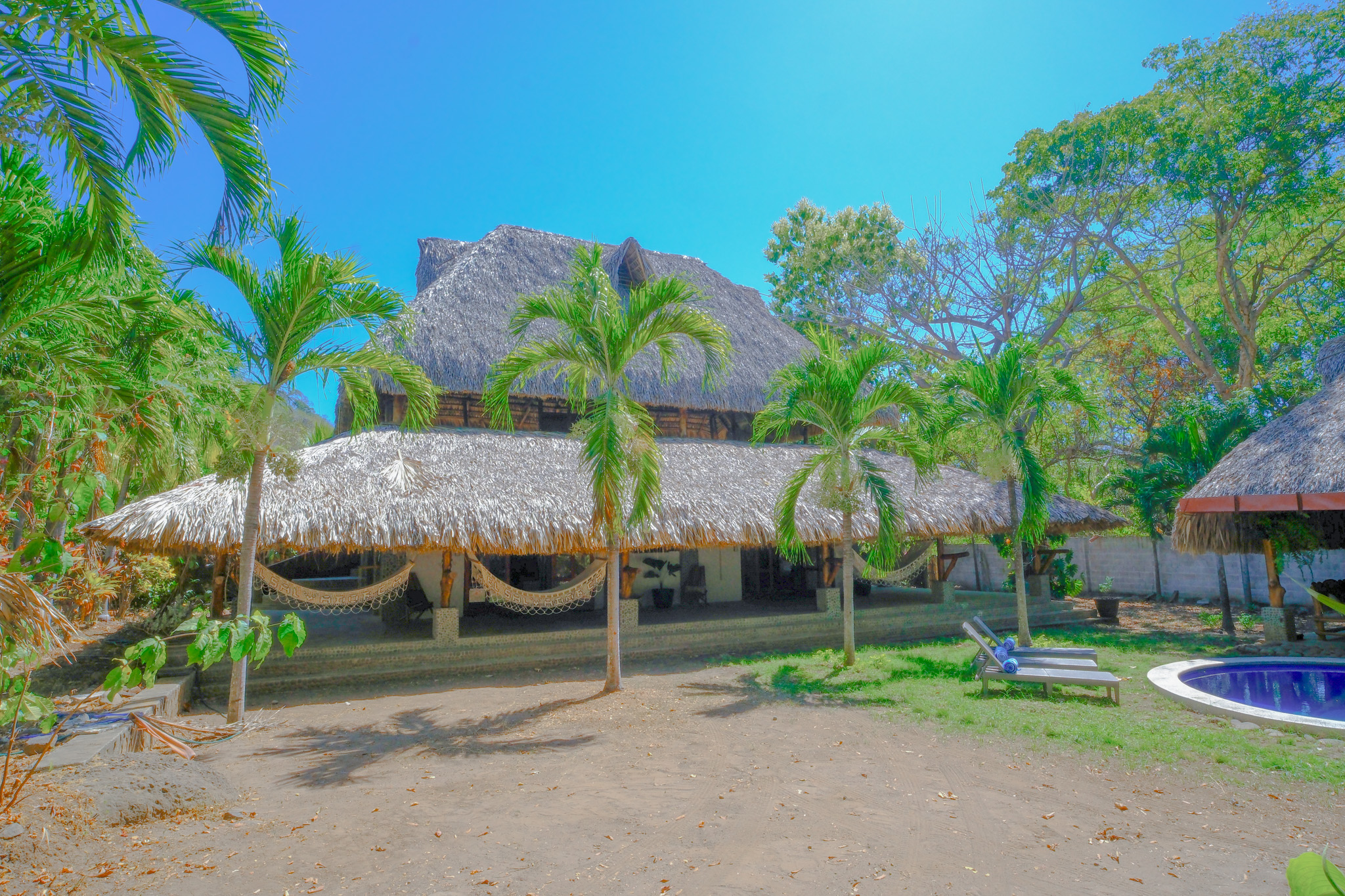 Vista exterior de Las Golondrinas KM59, el nuevo hotel surfer de la cadena argentina en El Salvador, rodeado de palmeras, jardines tropicales y áreas de descanso.