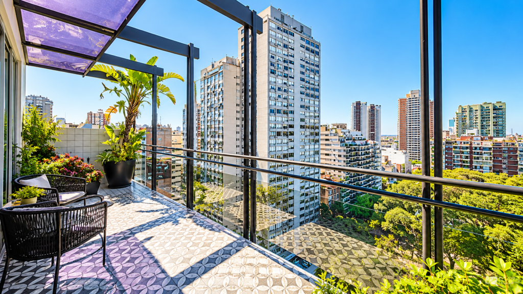 Balcón luminoso de un departamento con vista panorámica y edificios de la ciudad