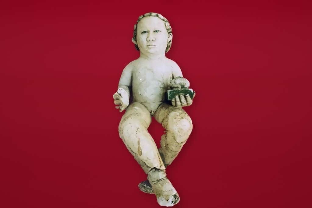 Escultura de un niño sentado sobre fondo rojo, atribuida a Miguel Ángel y conservada en el anonimato por una familia argentina, cuya autenticidad aún debe confirmarse