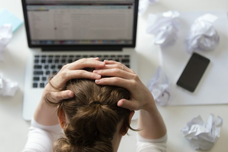 Mujer agotada frente a una computadora durante su jornada laboral, una imagen que refleja el estrés y el impacto del trabajo en la salud mental