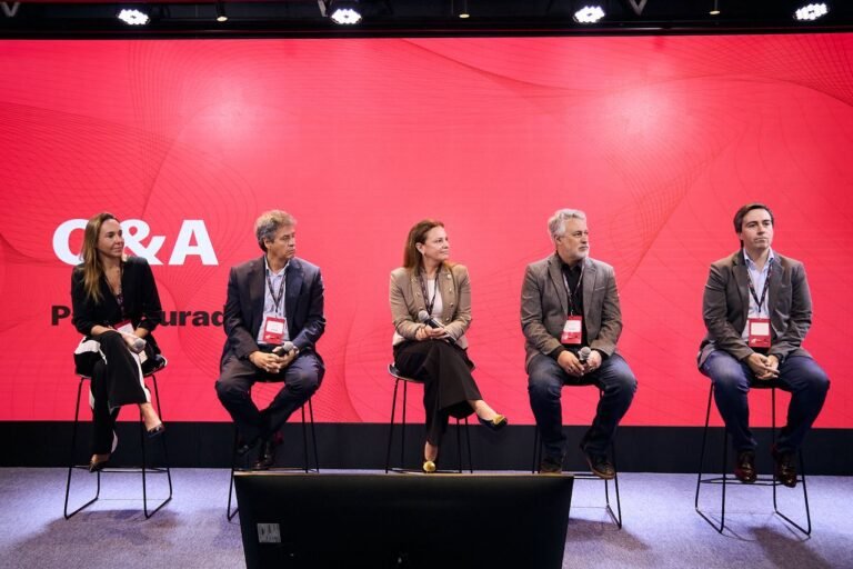 Cinco representantes del ámbito empresarial participan de un panel de preguntas y respuestas sobre un escenario con fondo rojo, en una jornada dedicada a la innovación y el mundo del trabajo